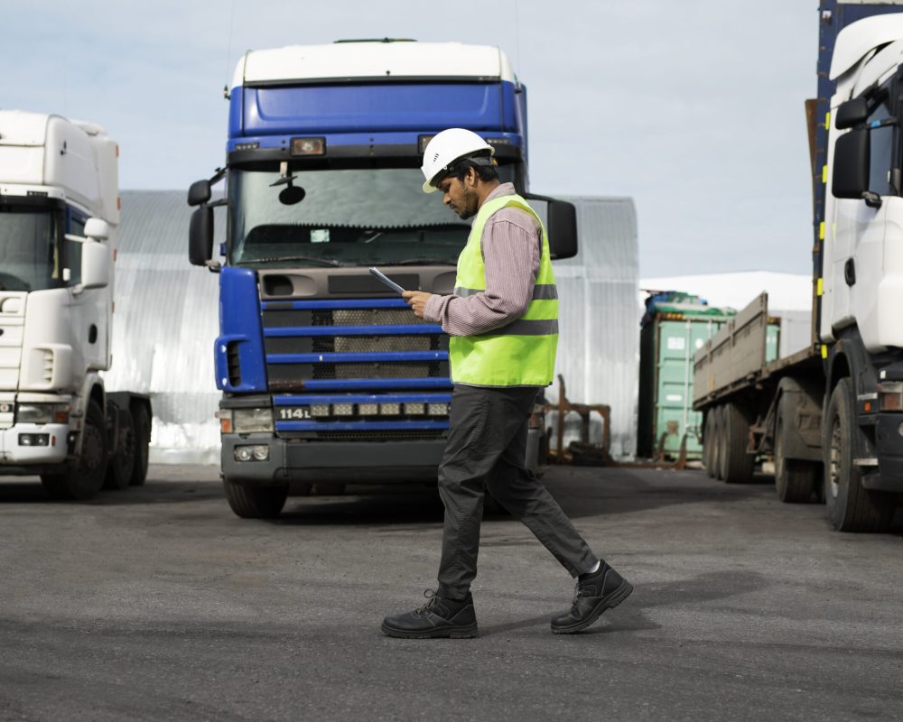 full-shot-man-walking-by-trucks-fleet